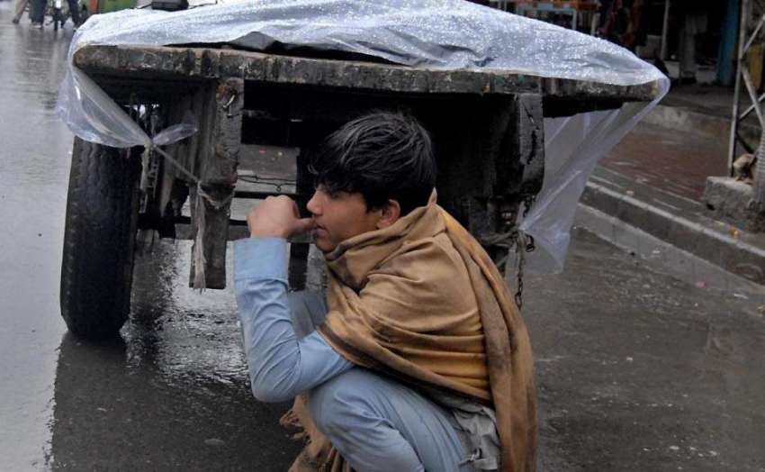 راولپنڈی: بارش کے دوران ایک محنت کش بارش سے بچنے کے لیے ریڑھے ..