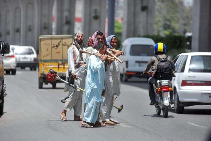اسلام آباد:مزدور اپنے اوزار اٹھائے مری روڈ کراس کر رہے ہیں۔