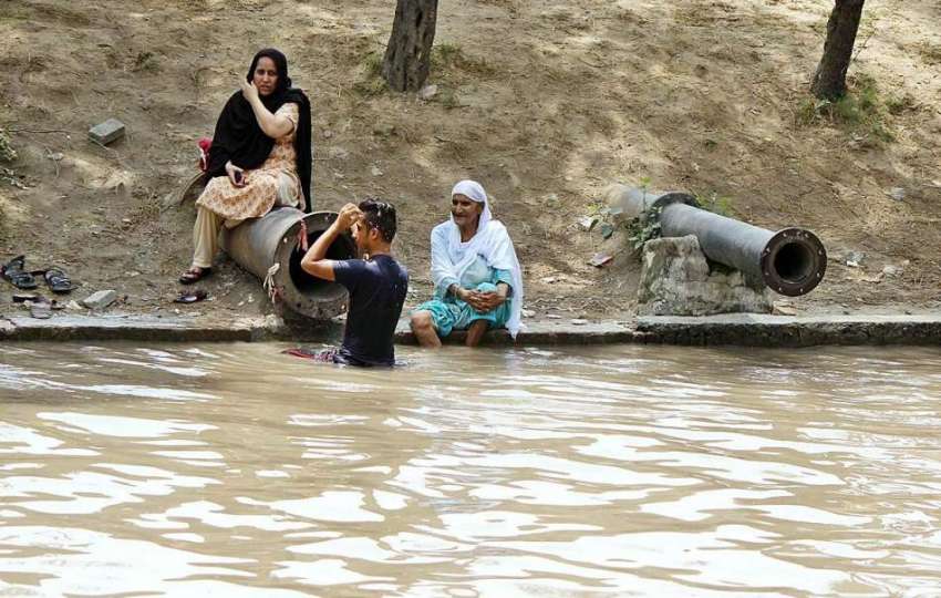 لاہور: گرمی کی شدت سے بچنے کے لیے ایک فیملی نہر کنارے بیٹھی ..