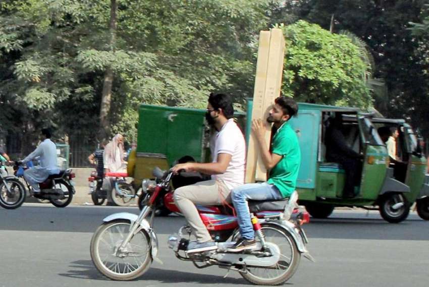 لاہور: شہری موٹر سائیکل پر بھاری سامان رکھے ماڈل روڈ سے گزر ..