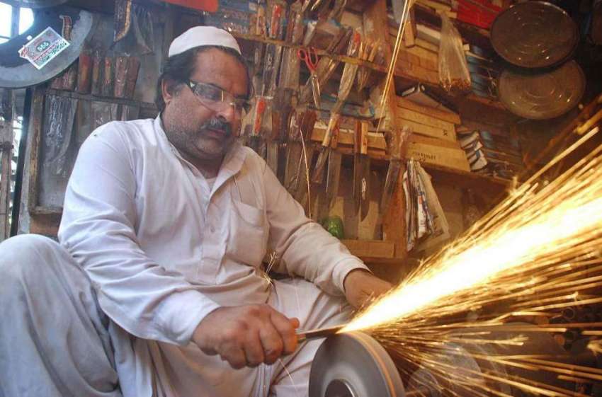 پشاور: عید قربان کے حوالے سے ایک دکاندار چھریاں تیز کر رہا ..