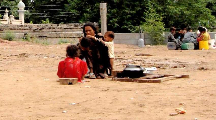 راولپنڈی: ایک خانہ بدوش خاتون اپنے بچے کے سر سے جوئیں تلاش ..