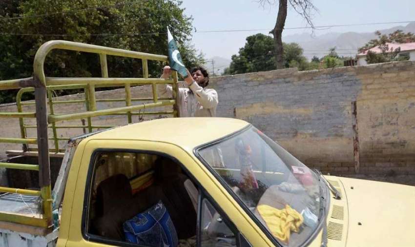 کوئٹہ: ایک شخص زرغون روڈ پر 14اگست کے لیے اپنے گاڑی میں قومی ..