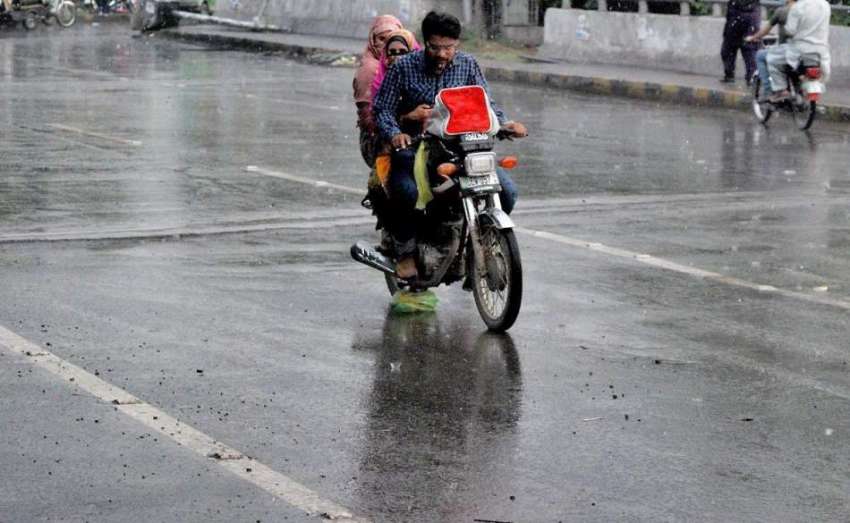 لاہور: مغلپورہ میں ہونے والی بارش کے دوران موٹر سائیکل سوار ..