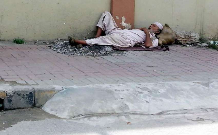 راولپنڈی: دنیا سے بے خبر ایک شخص فٹ پاتھ پر سو رہا ہے۔