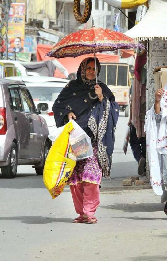 راولپنڈی: ایک خاتون گرمی کی شدت سے بچنے کے لیے چھتری تانے ..