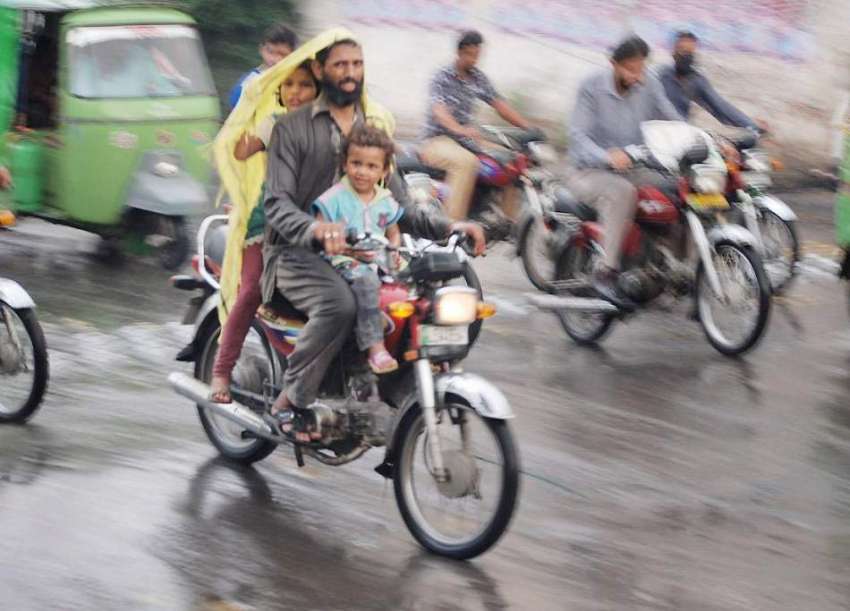 لاہور: موٹر سائیکل سوار بارش سے بچنے کے لیے پلاسٹک اوڑھے ..