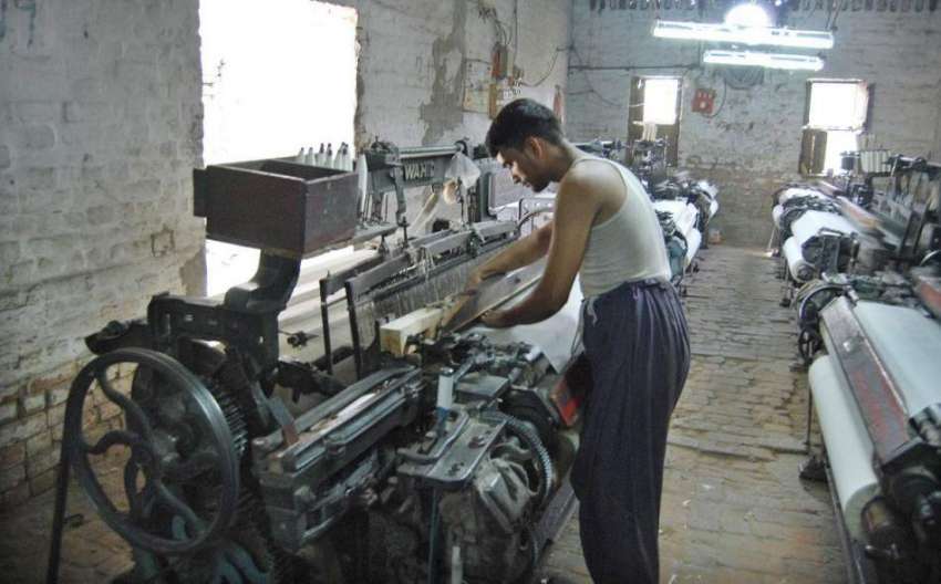 فیصل آباد: مزدور پاور لوم پر کام میں مصروف ہے۔