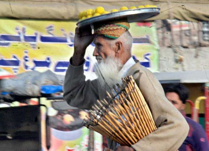 لاہور: ایک بزرگ محنت کش مٹھائی سر پر اٹھائے فروخت کرنے کے ..