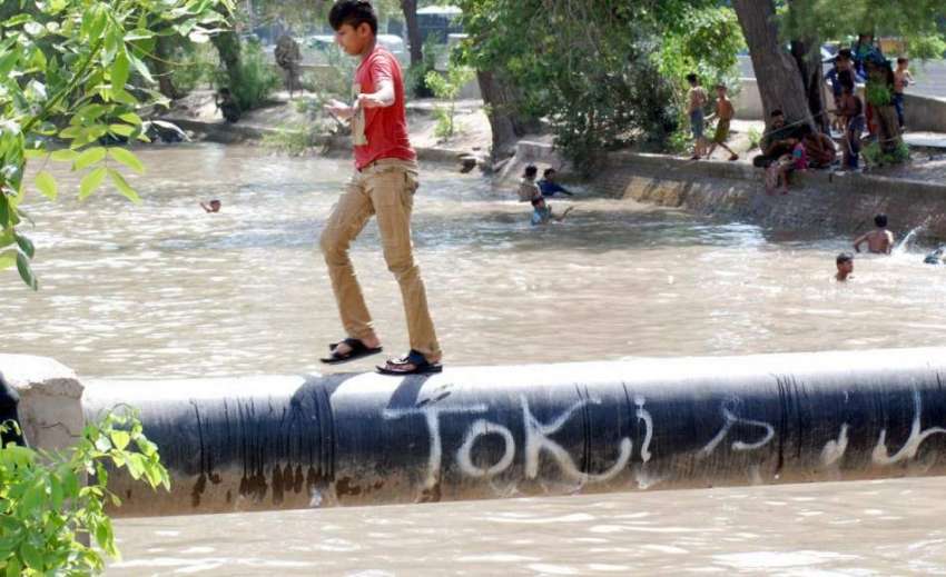 لاہور: ایک بچہ نہر کے اوپر لگے پائپ سے گزر رہا ہے۔