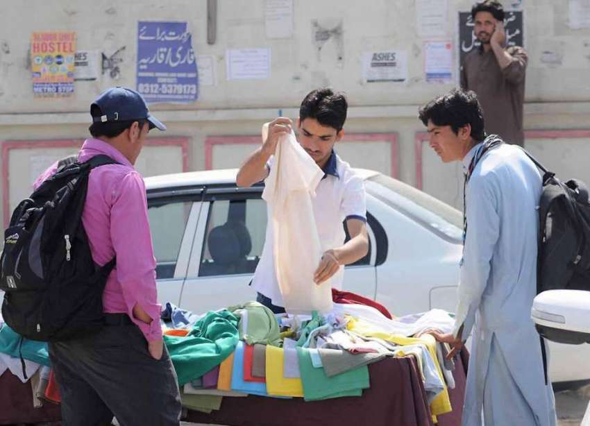اسلام آباد: نوجوان سڑک کنارے ایک سٹال سے ٹی شرٹس پسند کر ..