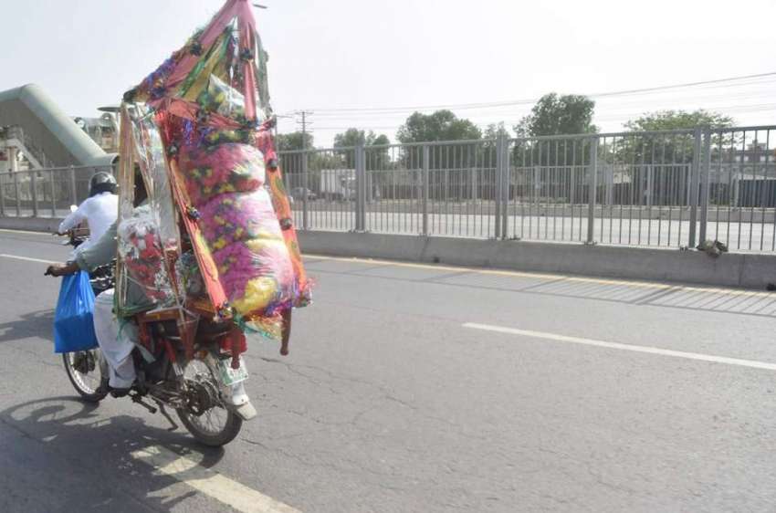 لاہور: ایک موٹر سائیکل سوار شہری سجاوٹ کا سامان خرید کر لیجا ..