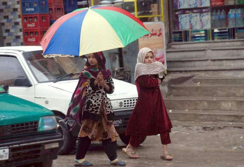 پشاور: بچیاں گرمی کی شدت سے بچنے کے لیے چھتری تانے جا رہی ..