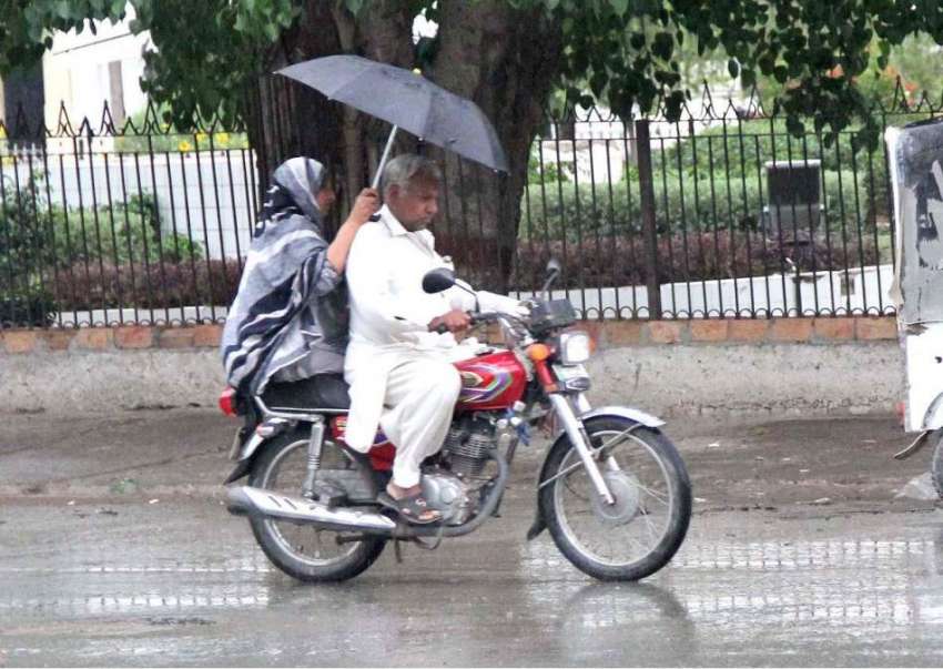 سرگودھا: موٹر سائیکل سوار فیملی بارش سے بچنے کے لیے چھتری ..