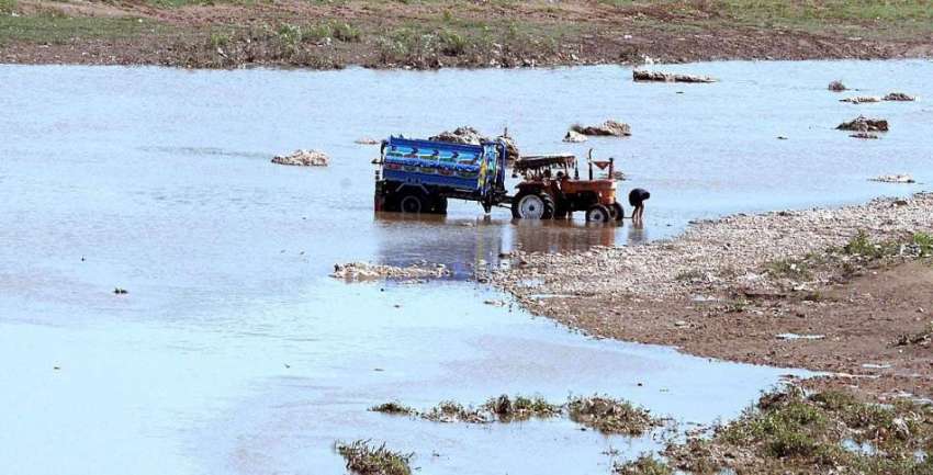راولپنڈی: ایک شخص دریائے سواں میں ٹریکٹر ٹرالی دھو رہا ہے۔