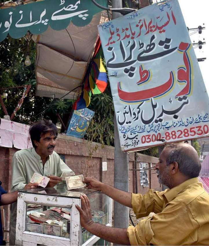 لاہور: ایک شخص سڑک کنارے نئے کرنسی چینچ کا سٹال لگائے بیٹھا ..
