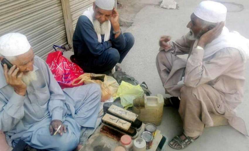 لاہور: ایک بزرگ موچی فارغ اوقات میں فون پر بات کر رہا ہے۔