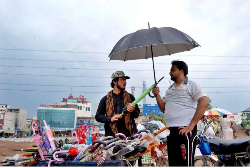 اسلام آباد: سڑک کنارے لگے سٹال سے شہری ایک سٹال سے چھتری ..