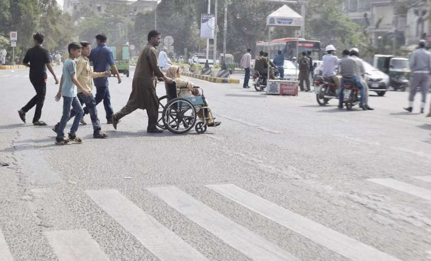 لاہور: ایک شہری اپنی بیمار والدہ کو وہیل چہیئر پر بٹھائے ..