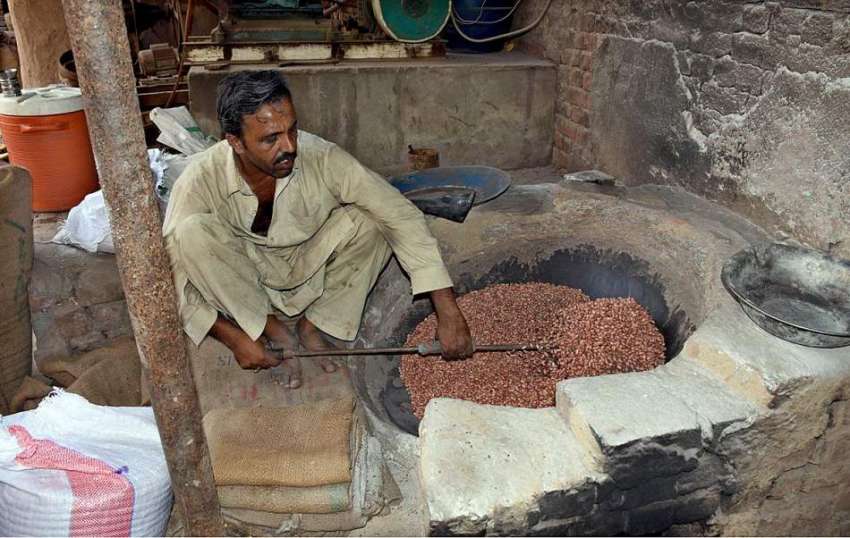 لاہور: محنت کش فروخت کے لیے مونگ پھلی بھون رہا ہے۔