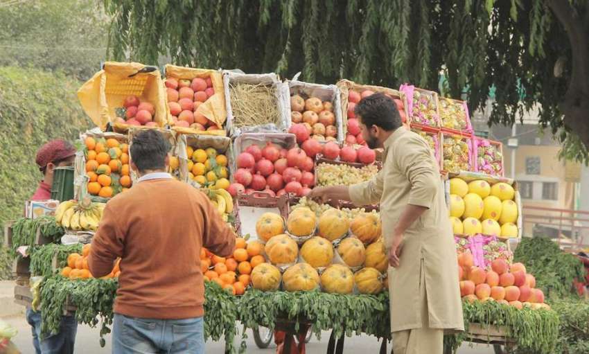 لاہور: شادمان چوک میں پھل فروش گاہکوں کو متوجہ کرنے کے لیے ..
