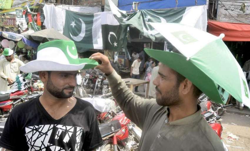 لاہور: اردو بازار میں ایک شخص قومی پرچم کے رنگوں والی ٹوپی ..