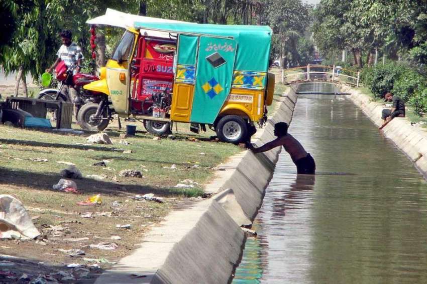 فیصل آباد: رکشہ ڈرائیور نہر کے پانی سے رکشہ دھو رہا ہے۔