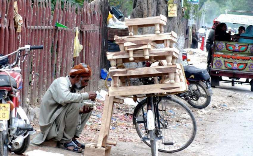 لاہور: لکڑی کی چوکیاں فروخت کرنے والا محنت کش سڑک کنارے بیٹھا ..