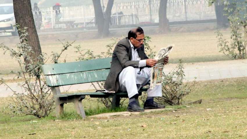 لاہور: جیلانی پارک میں ایک شہری دھوپ میں بیٹھا اخبار پڑھ ..