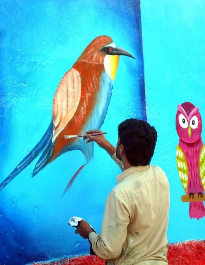 چنیوٹ: ایک آرٹسٹ سڑک کنارے دیوار پر پینٹنگ بنا رہا ہے۔