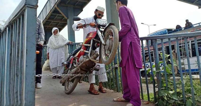 راولپنڈی: ایک شخص پیدل سڑک کراس کرنے والے پل پر لگی چین سے ..