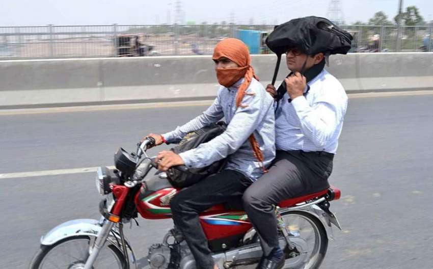 لاہور: موٹر سائیکل سوار گرمی کی شدت سے بچنے کے لیے منہ پر ..