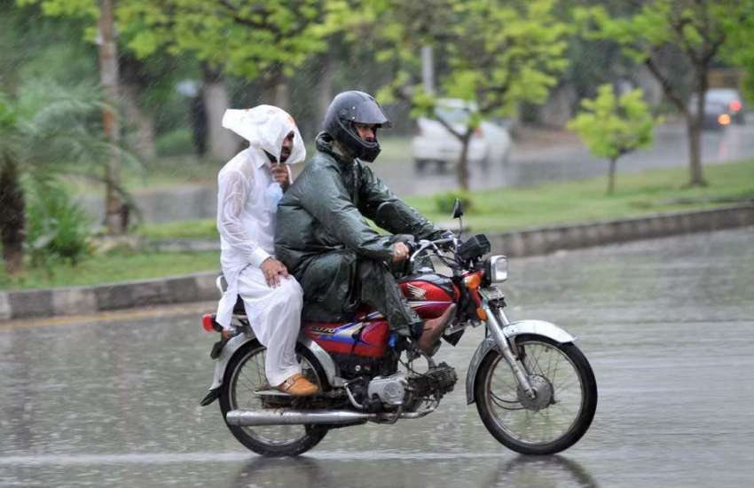 اسلام آباد: موٹر سائیکل سوار برساتی پہنے بارش کے دوران اپنی ..