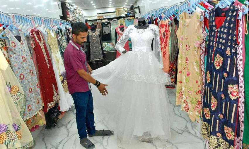 فیصل آباد: دکاندار گاہکوں کو متوجہ کرنے کے لیے کپڑے سجا رہا ..