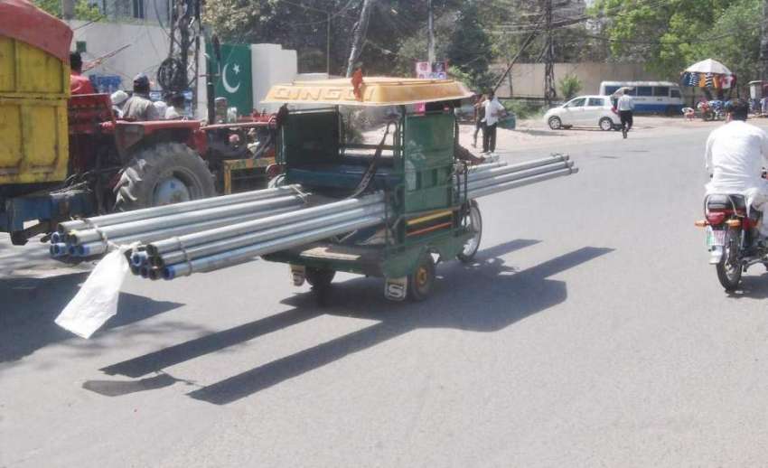 لاہور: ایک شخص چنگچی رکشے میں لوہے کے پائپ رکھ کر لیجا رہا ..