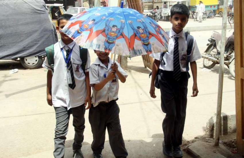 کراچی: سکول سے چھٹی کے بعد بچے چھتری تانے گھروں کو جا رہے ..