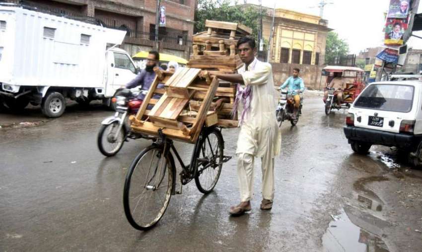 لاہور: ایک محنت کش سائیکل پر لکڑی کی چوکیاں فروخت کررہا ہے۔