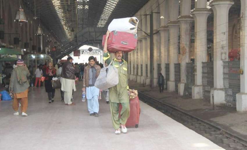 لاہور: ریلوے اسٹیشن پر قلی مسافر کا بھاری سامان اٹھا کر پلیٹ ..