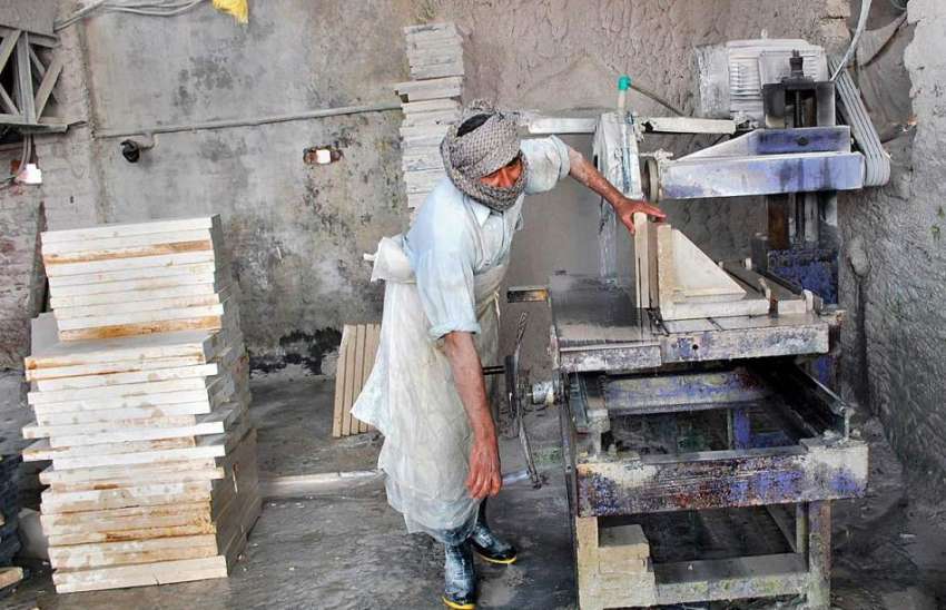 فیصل آباد: مزدور ماربل فیکٹری میں پتھر کاٹنے میں مصروف ہے۔