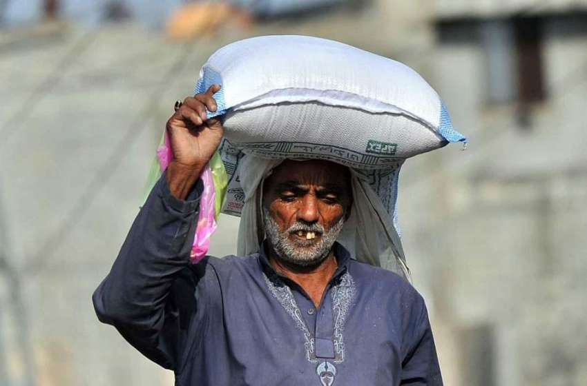 اسلام آباد: ایک معمر شخص سر پر آٹے کا تھیلا اٹھائے گھر کی ..