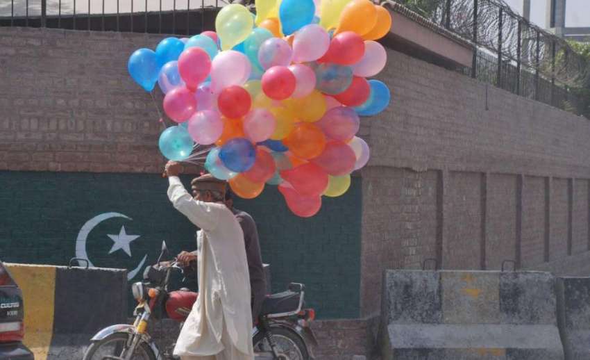 لاہور: ایک محنت کش غبارے فروخت کرنے کے لیے جا رہا ہے۔