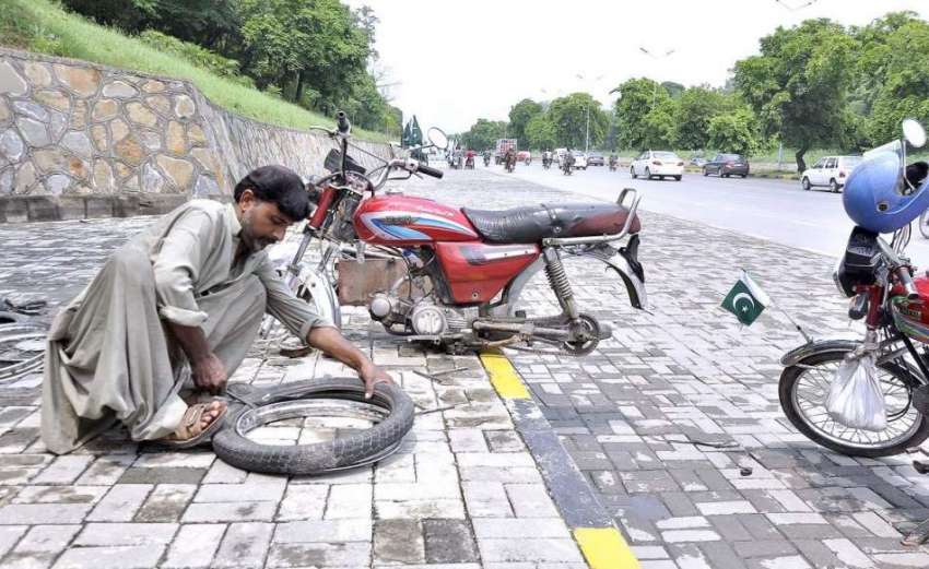 اسلام آباد: محنت کش سڑک کنارے موٹر سائیکل کے ٹائر کوپنکچر ..