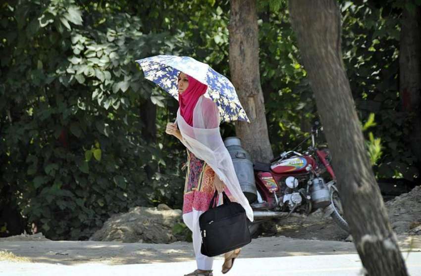 اسلام آباد: خاتون گرمی کی شدت سے بچنے کے لیے چھتری تانے جا ..