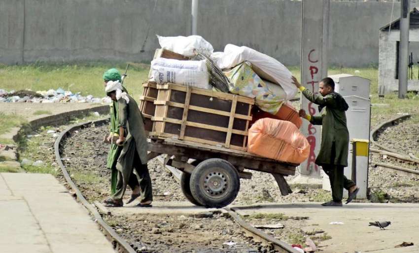 لاہور: ریلوے اسٹین پر قلی ہتھ ریڑھے پر مسافروں کا سامان رکھ ..