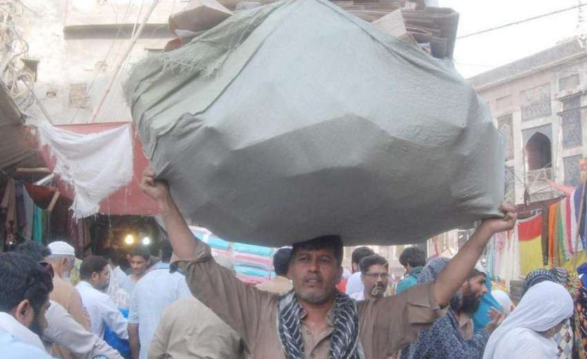 لاہور: ایک شخص سر پر بھاری سامان اٹھا کر لیجا رہا ہے۔