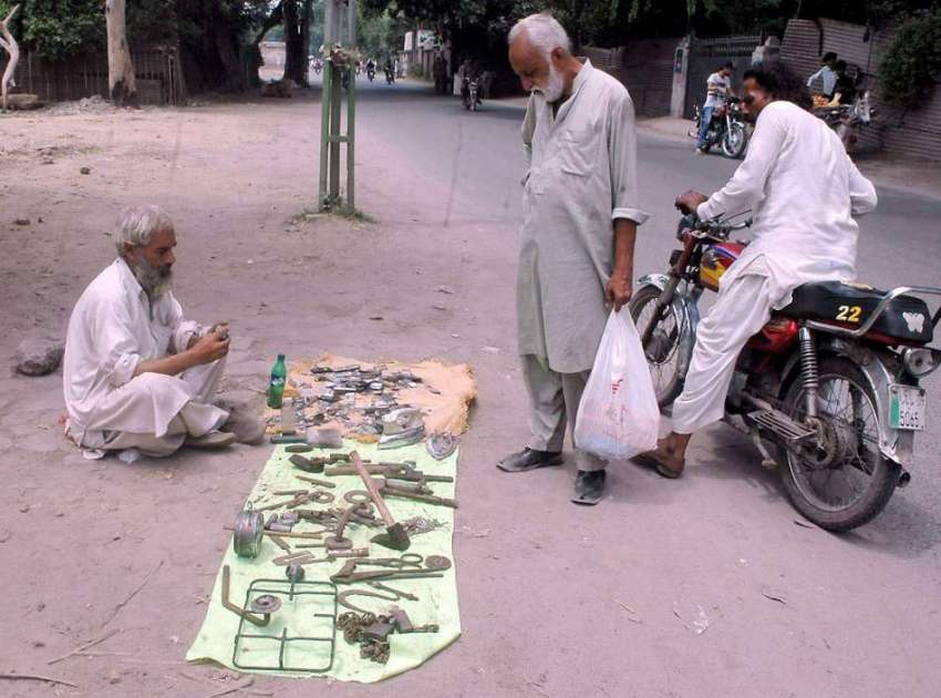لاہور: ایک شخص سرک کنارے بیٹھا پرانی اشیاء فروخت کر رہا ہے۔