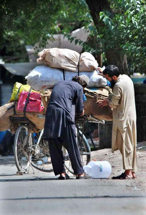 اسلام آباد: ایک محنت کش اپنی سائیکل پر مختلف اشیاء لوڈ کر ..