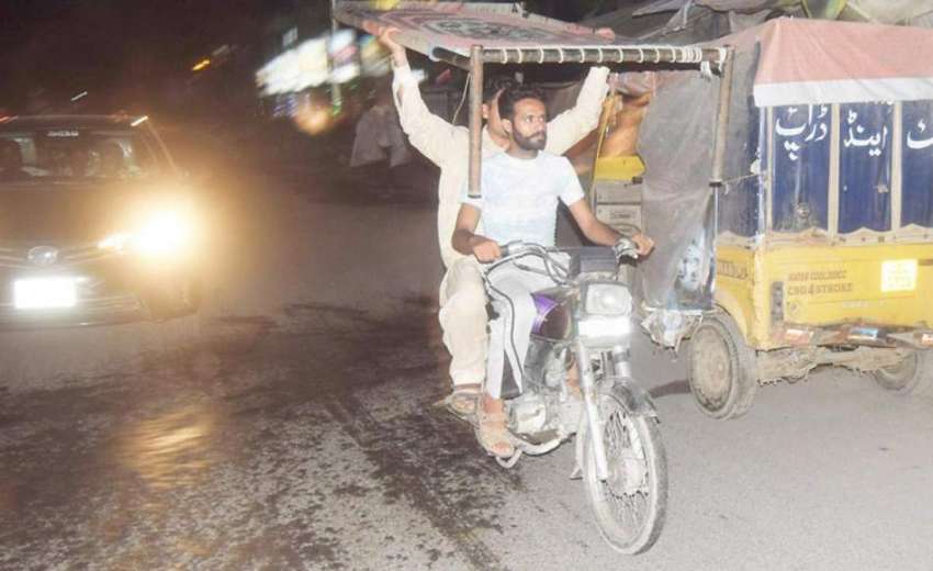 لاہور: موٹر سائیکل سوار نوجوان چارپائی لئے جا رہے ہیں۔