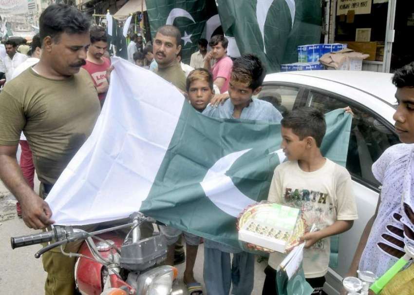 لاہور: اردو بازار میں ایک پولیس اہلکار قومی پرچم خریدنے ..