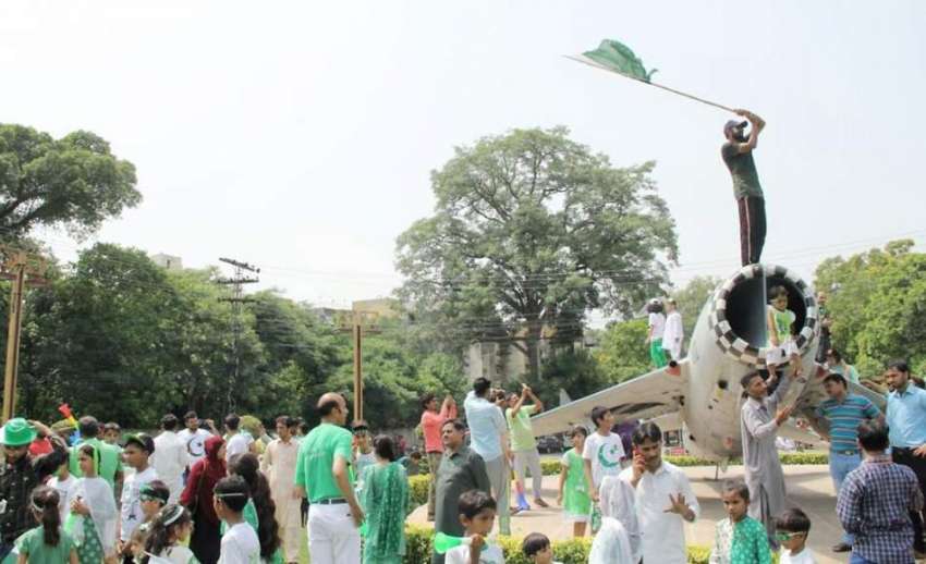 لاہور: ایک شخص چائنہ چوک میں نصب طیارے کے اوپر چڑھ کر قومی ..